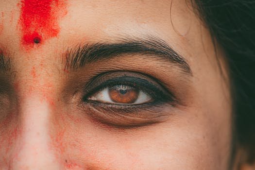 Detailed close-up of an Indian woman's eye with traditional red sindoor, emphasizing cultural beauty.